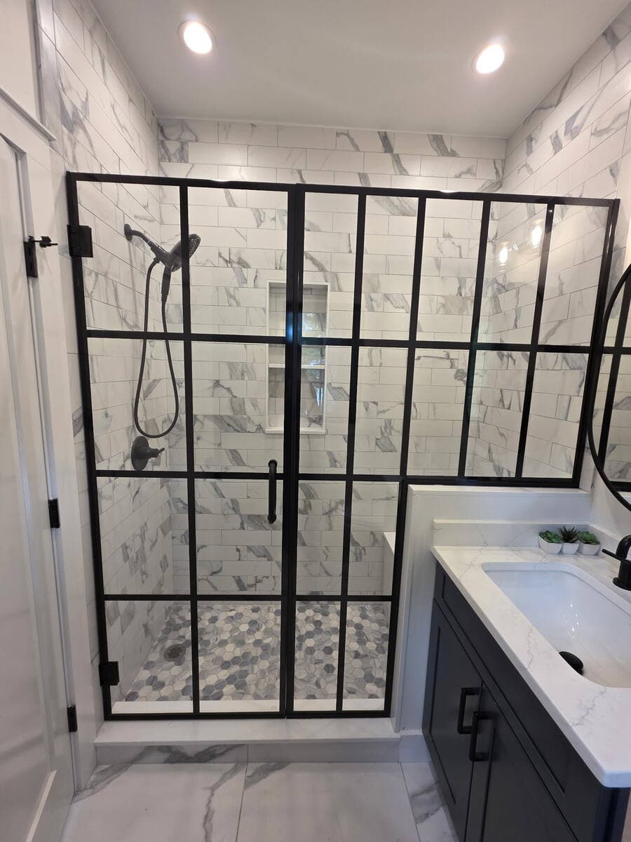 Black-framed grid shower enclosure with marble tile