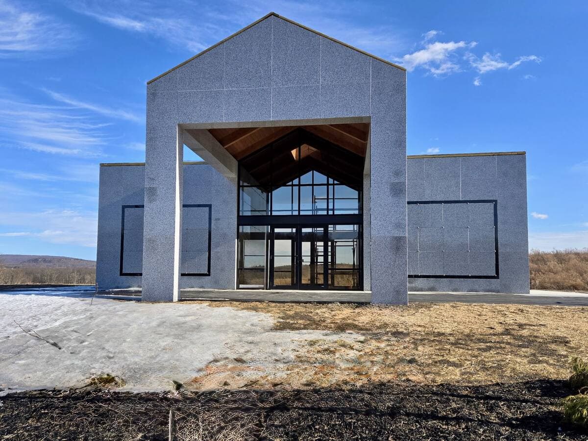 Granite building with full-height glass gable entrance